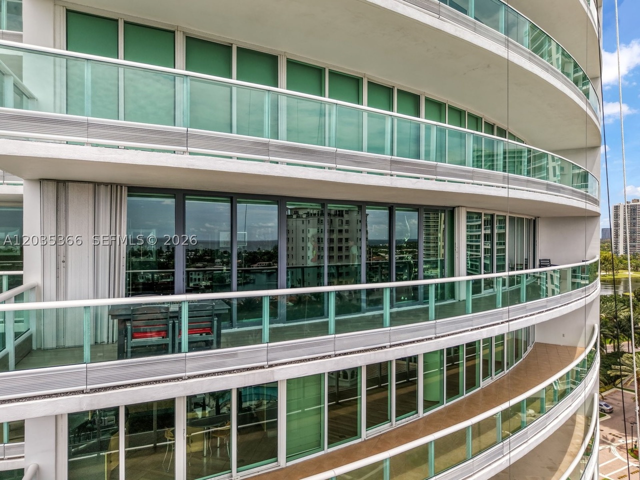 Exterior of the Porto Vita South Tower, its curved green-glass facade rising in stacked, glass-railed terraces