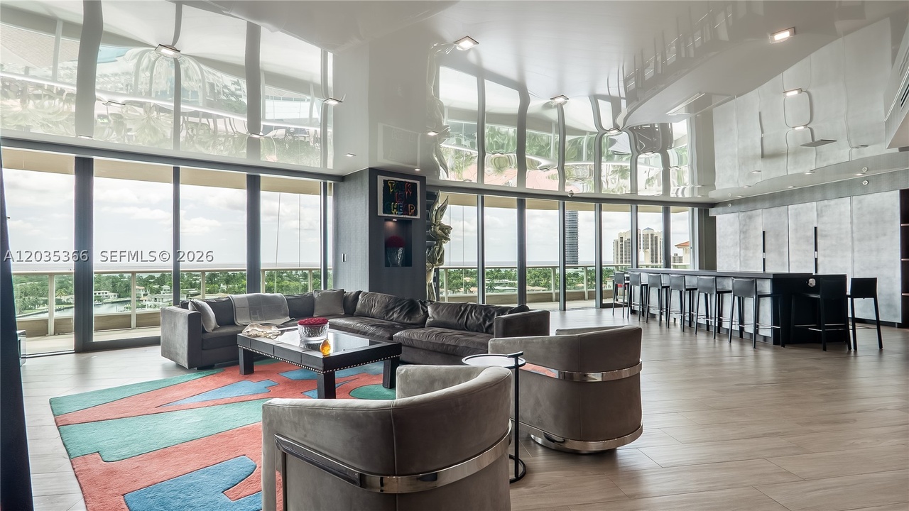 The double-height great room at Porto Vita Residence 1205, with a custom mirror-gloss ceiling reflecting the floor-to-ceiling glass wall and the Intracoastal view beyond